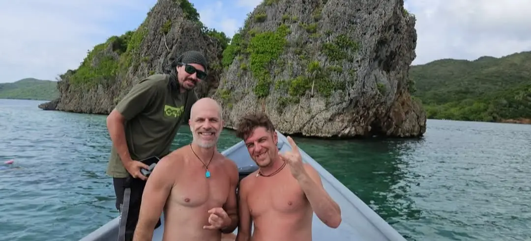 Trois voyageurs en bateau devant de spectaculaires formations rocheuses karstiques au large de Roatán