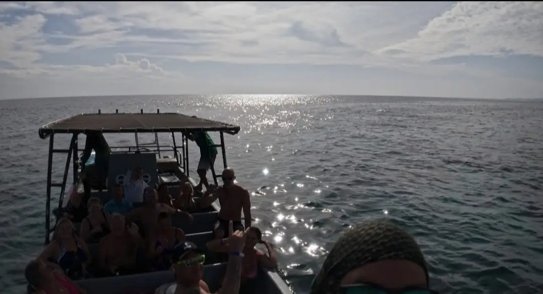 Sortie en bateau sous la toile vers le large, reflets argentés sur la mer au soleil couchant