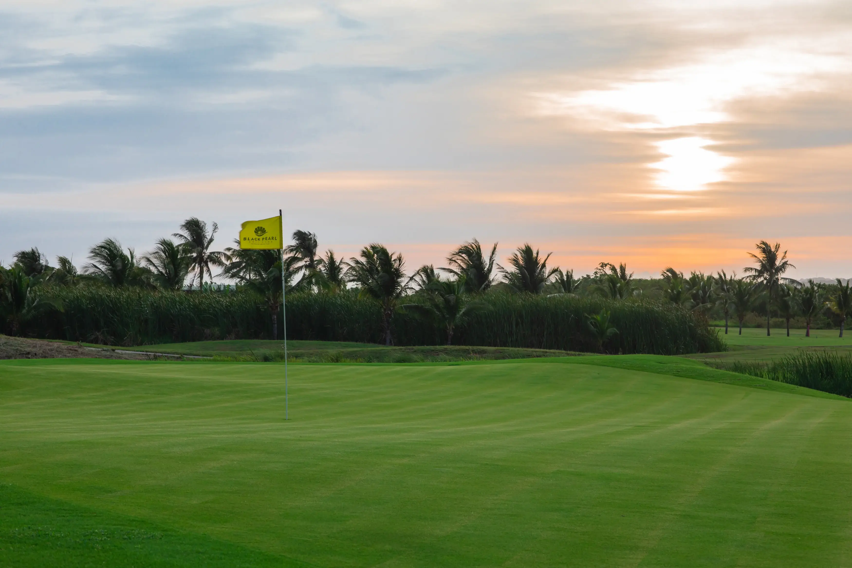 The green and flag at Black Pearl Golf Course, Pristine Bay, Roatán, at sunset