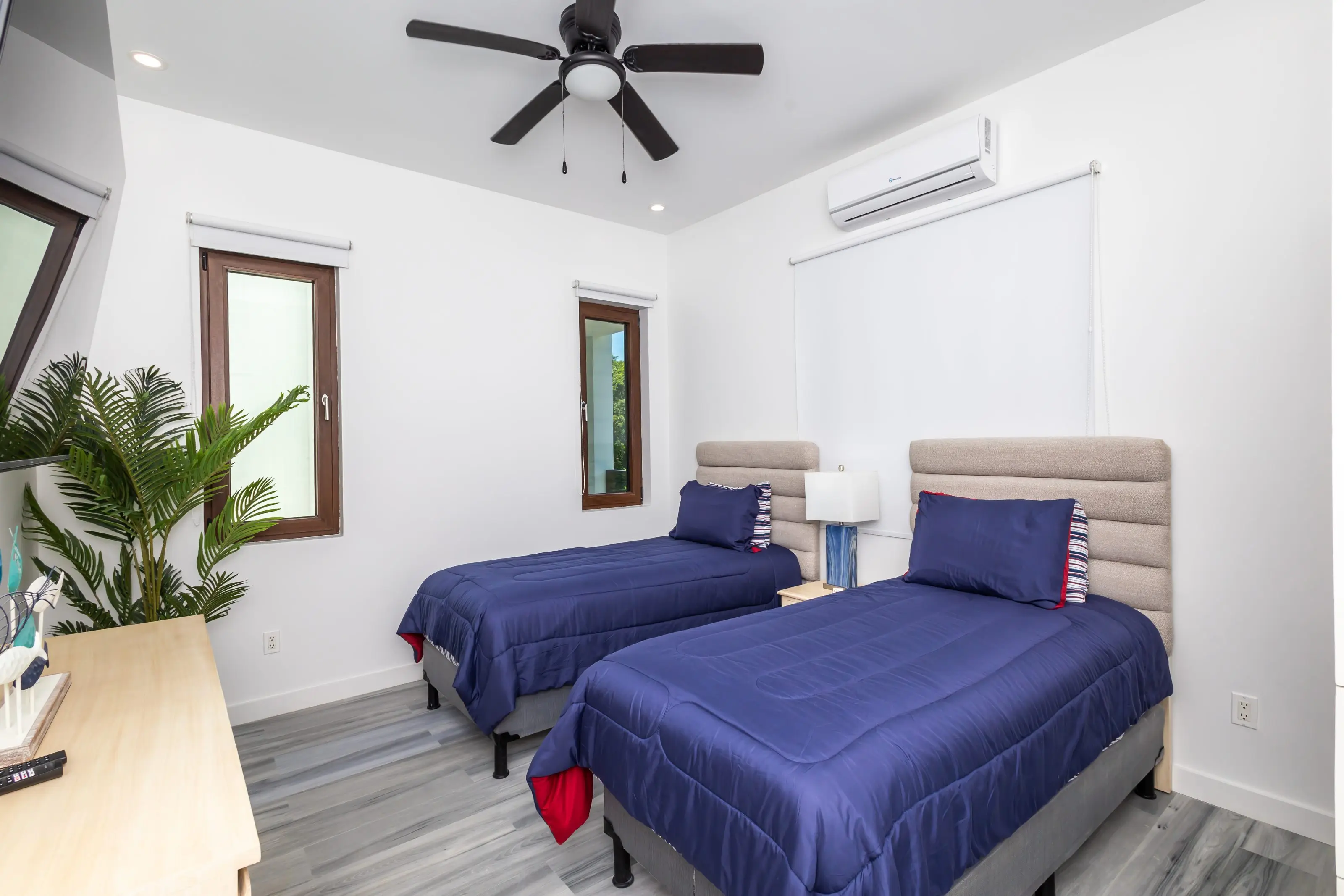 Twin-bed room with ceiling fan and air conditioning, grey plank flooring