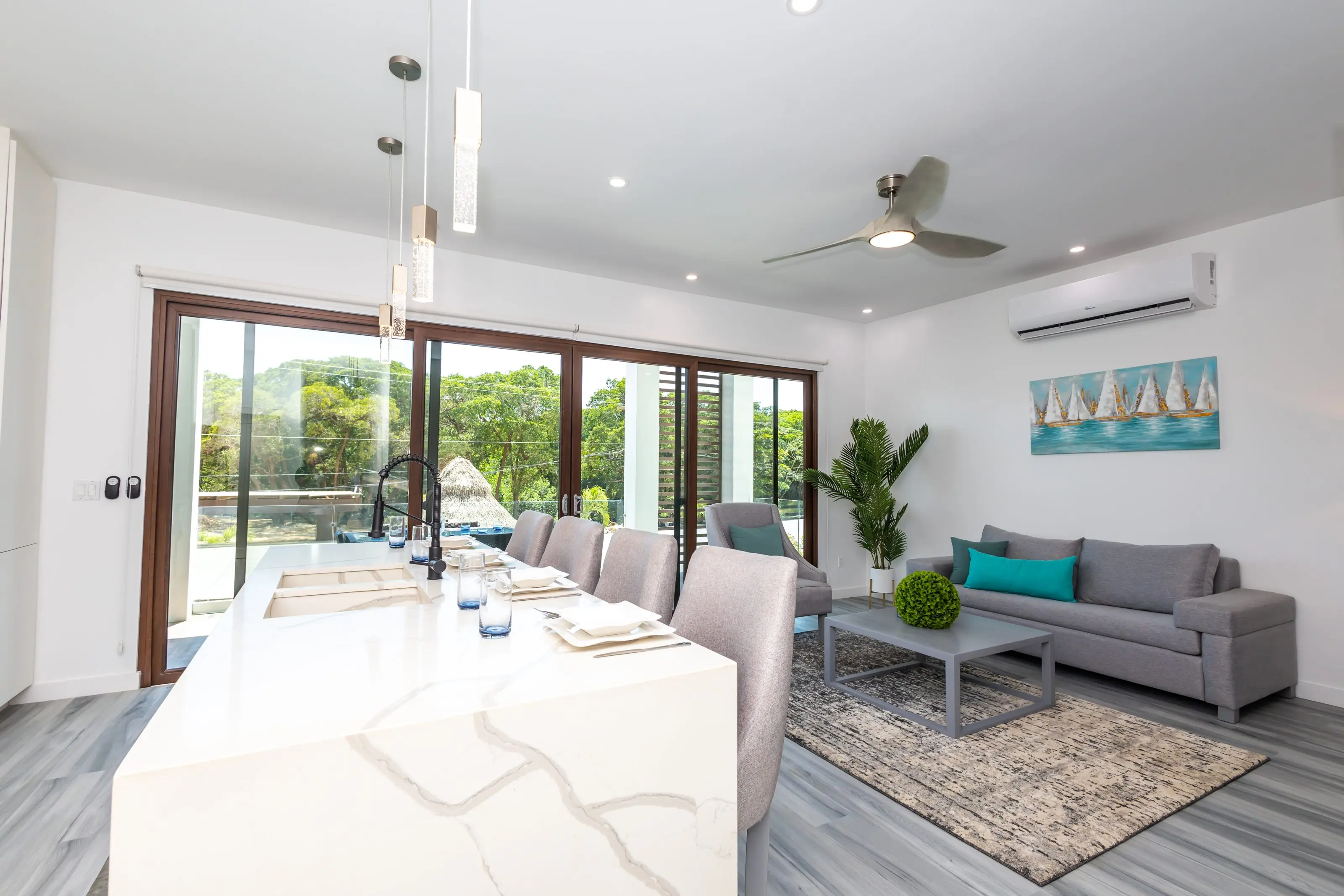 An Acqua di Mare apartment: full kitchen with marble island, living room and sliding doors onto greenery