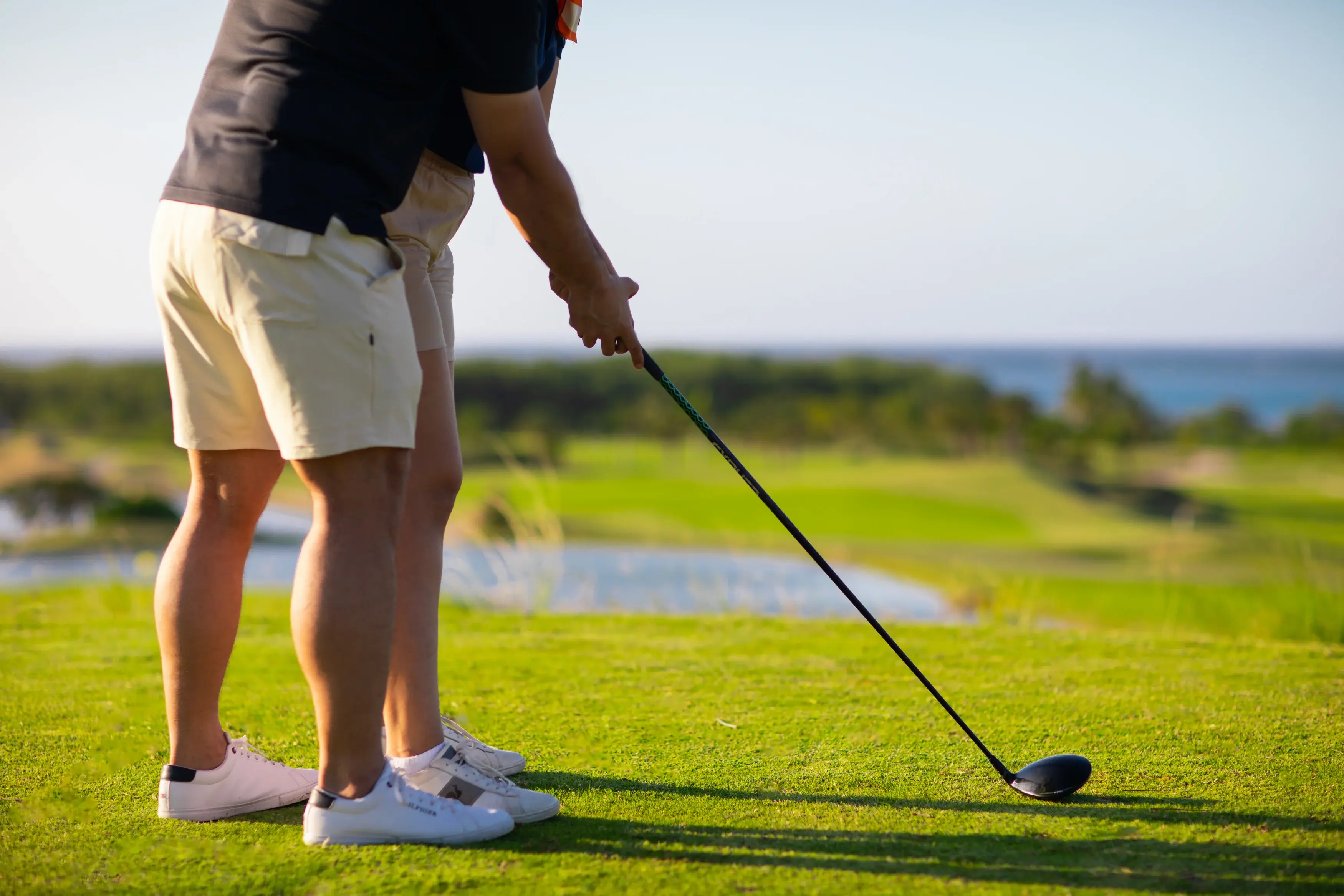 A golfer teeing off at Black Pearl golf course, with the Caribbean Sea in the background