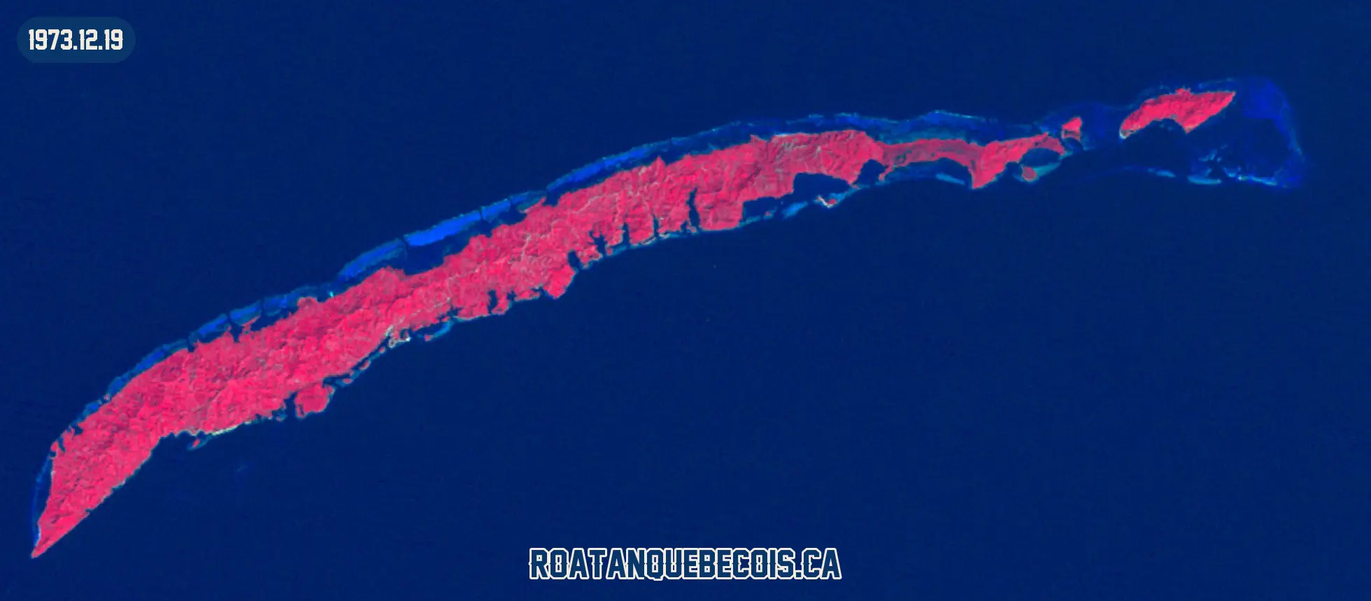 Roatán vue du ciel le 19 décembre 1973, en fausse couleur infrarouge où la végétation apparaît en rouge : l'île entière, son récif et les zones bâties