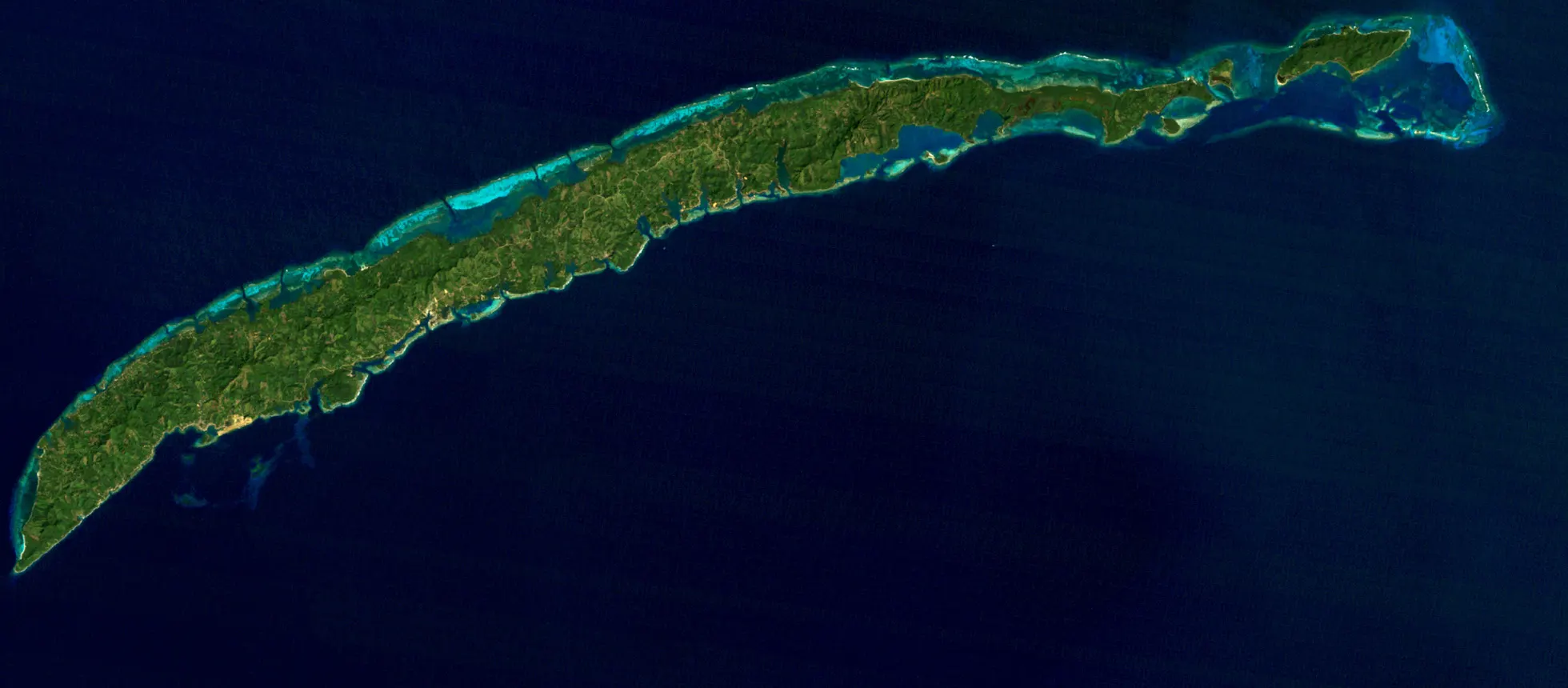 Roatán vue par Landsat 5 le 1er février 1985, en couleurs naturelles : l'île est verte d'un bout à l'autre, presque aucune tache pâle
