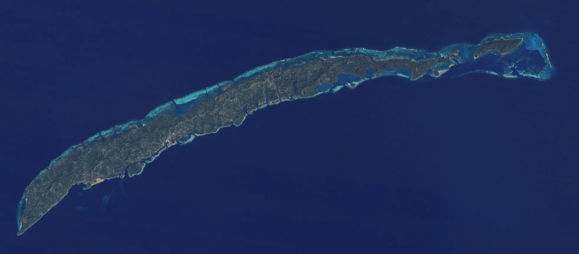 Roatán vue par le satellite Landsat 5 le 1er février 1985 : l'île est presque entièrement verte, le bâti gris tient dans quelques taches