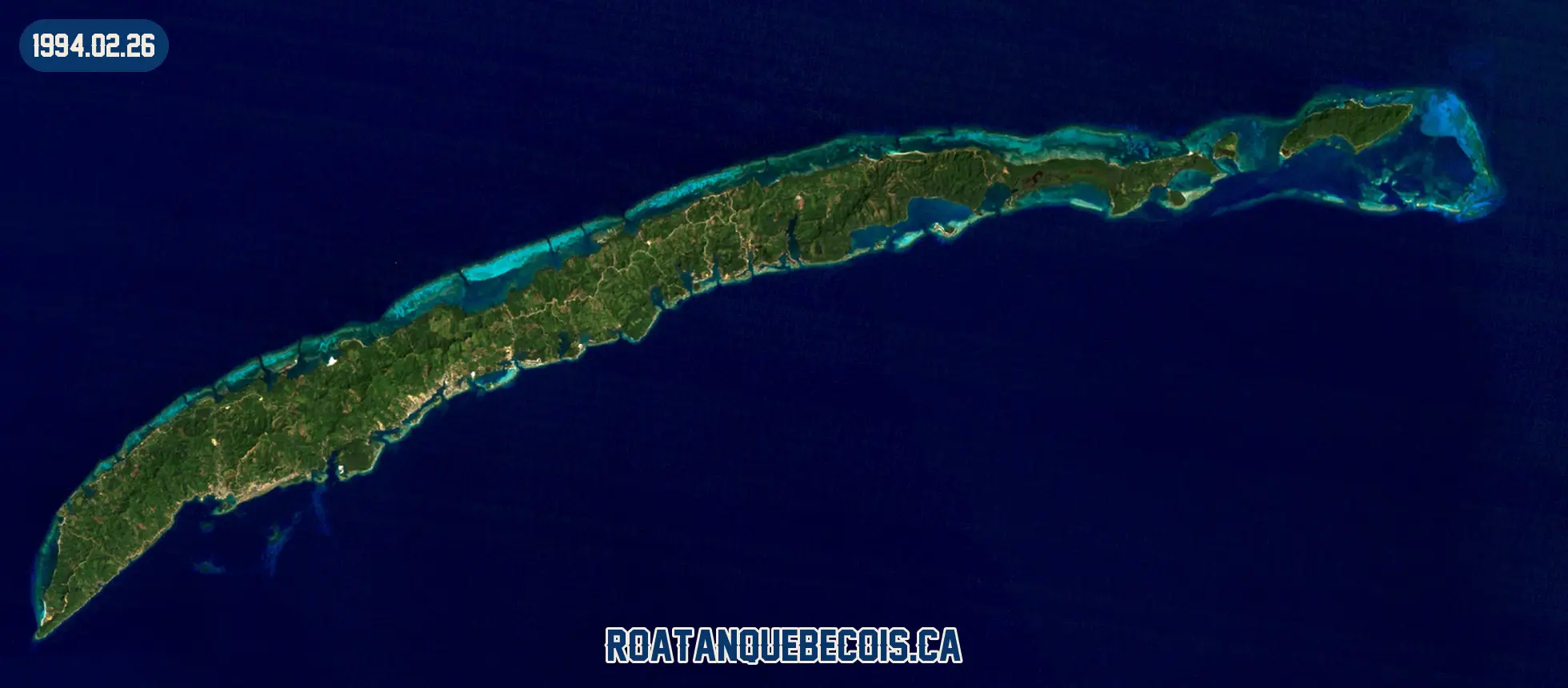 Roatán vue du ciel le 26 février 1994 : l'île entière, son récif et les zones bâties