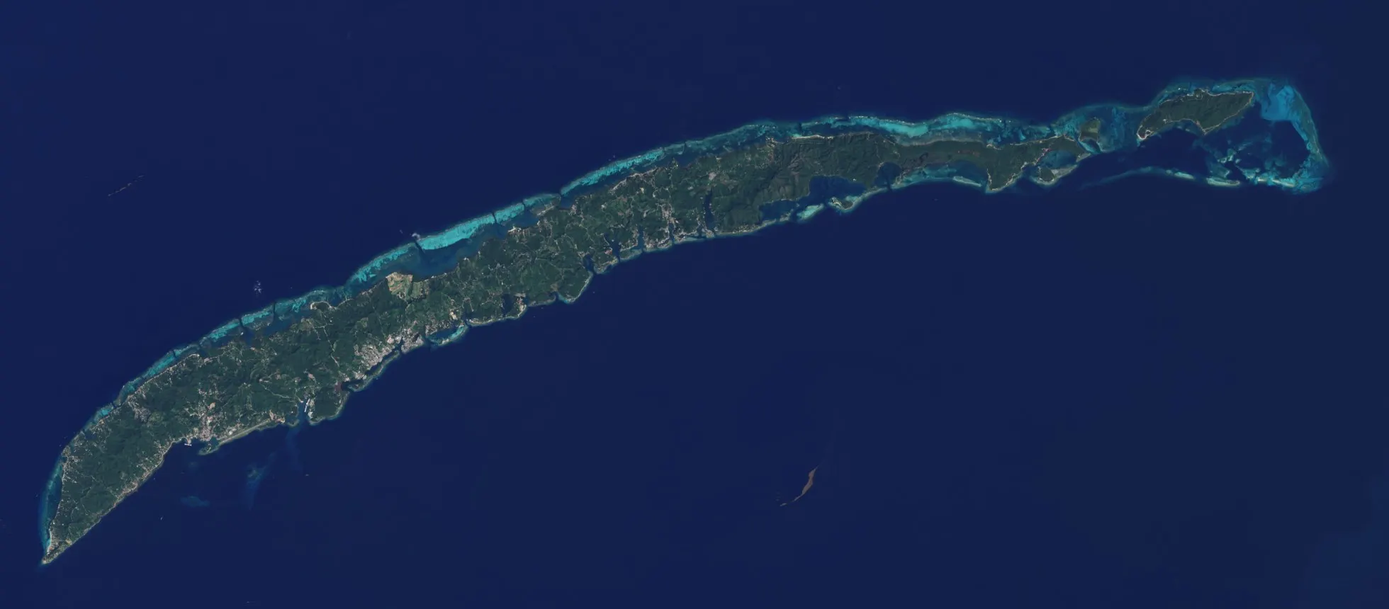 Roatán vue par le satellite Landsat 8 le 5 février 2015 : le bâti gris court le long des côtes, surtout dans l'ouest de l'île