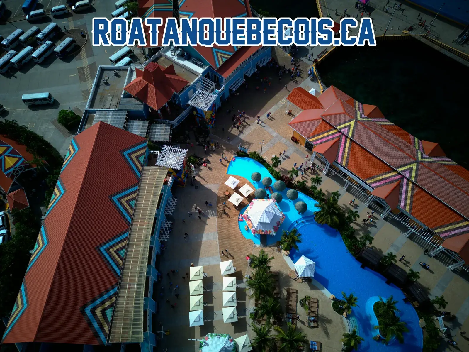 The painted roofs of the Port of Roatán terminal, the pool, its cabanas and the coach park beyond