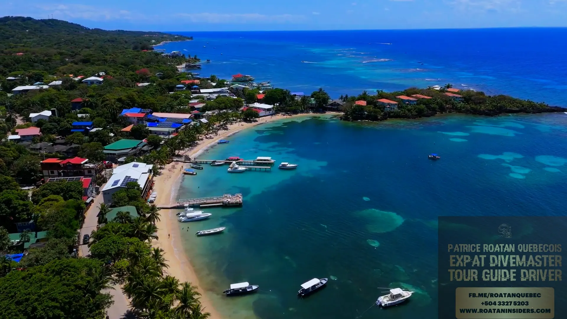 Vue aérienne du village de West End à Roatán : la plage en croissant, les quais, les bateaux et le récif au large